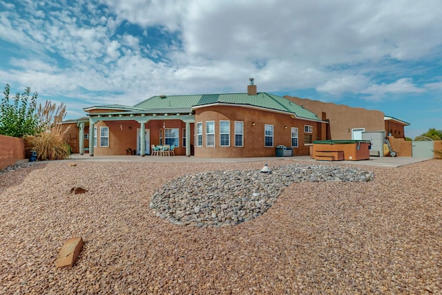 rear view of property with a hot tub and a patio area