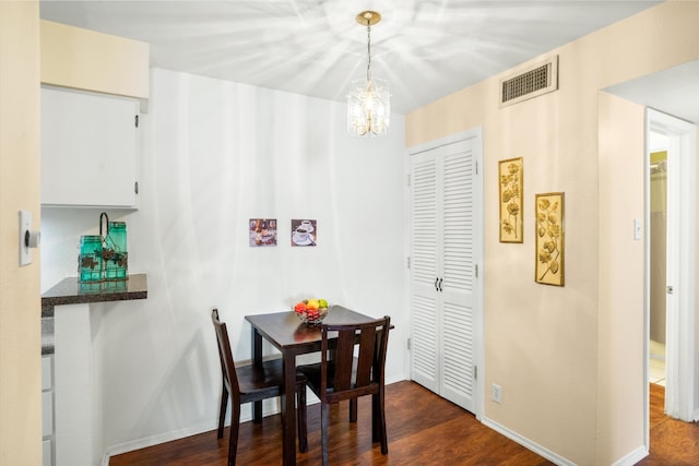 dining room with dark hardwood / wood-style floors and a notable chandelier