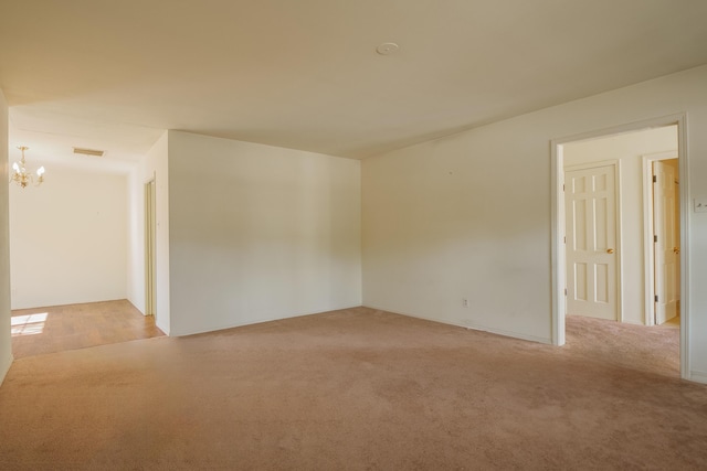 empty room with light carpet and a notable chandelier