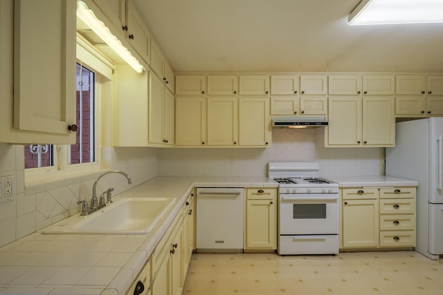 kitchen with sink, white appliances, cream cabinetry, and decorative backsplash