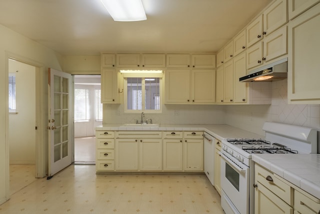 kitchen with sink, tile countertops, white appliances, and cream cabinetry