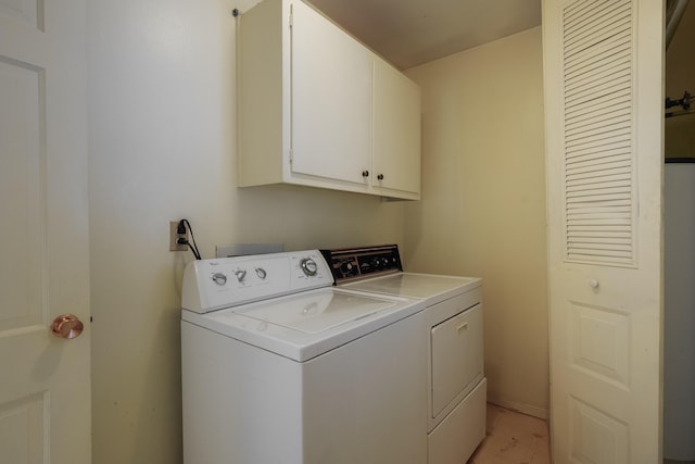 clothes washing area featuring washer and dryer and cabinets