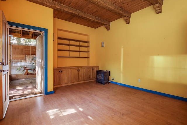 empty room with a wood stove, light hardwood / wood-style flooring, beamed ceiling, and wood ceiling