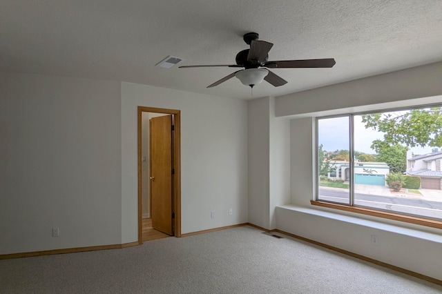 empty room with a textured ceiling, light colored carpet, and ceiling fan