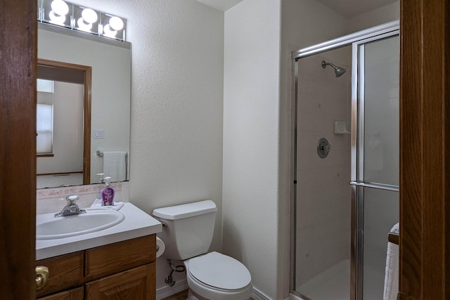 bathroom featuring vanity, a shower with shower door, and toilet