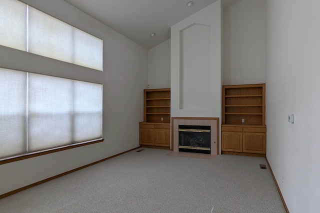 unfurnished living room with light carpet, high vaulted ceiling, and a tile fireplace