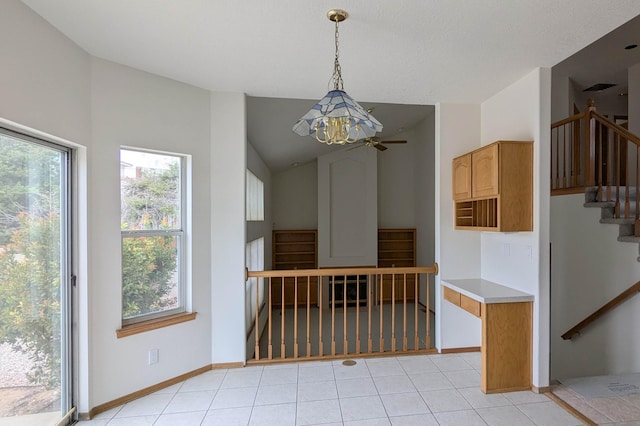 unfurnished dining area with lofted ceiling, an inviting chandelier, and light tile patterned floors