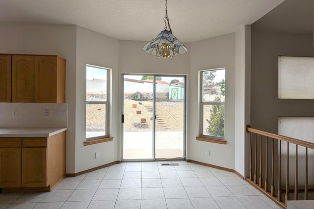 entryway with light tile patterned flooring, a textured ceiling, and a chandelier