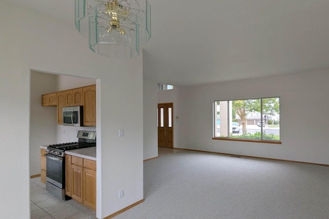 kitchen with a notable chandelier, stainless steel appliances, and light colored carpet