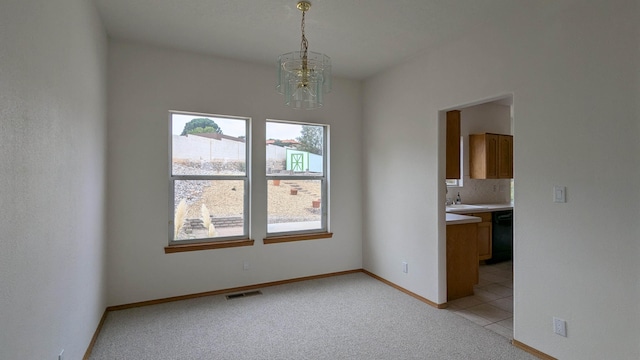 unfurnished dining area with sink, an inviting chandelier, and light colored carpet