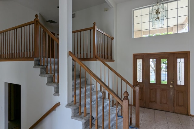 tiled entryway featuring an inviting chandelier and a towering ceiling