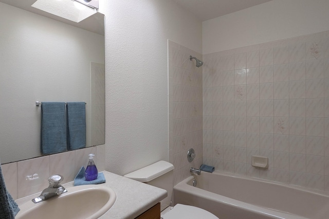 full bathroom with toilet, tiled shower / bath combo, vanity, and a skylight