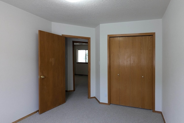 unfurnished bedroom with a closet, a textured ceiling, and light colored carpet