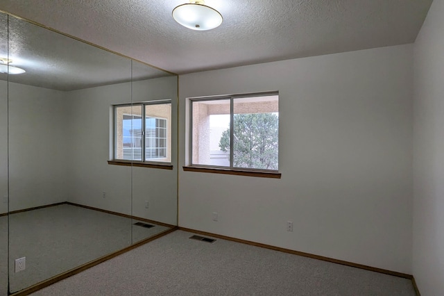 empty room with a textured ceiling and carpet flooring