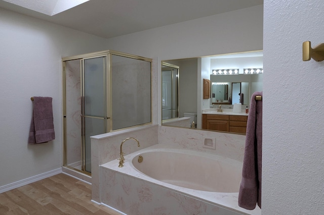 bathroom featuring vanity, hardwood / wood-style flooring, independent shower and bath, and a skylight