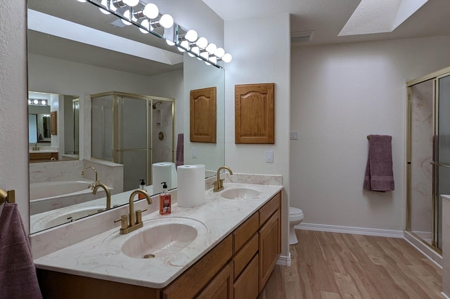 full bathroom featuring a skylight, independent shower and bath, toilet, vanity, and hardwood / wood-style flooring