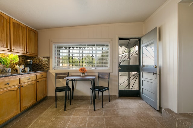 tiled dining room with lofted ceiling and ornamental molding