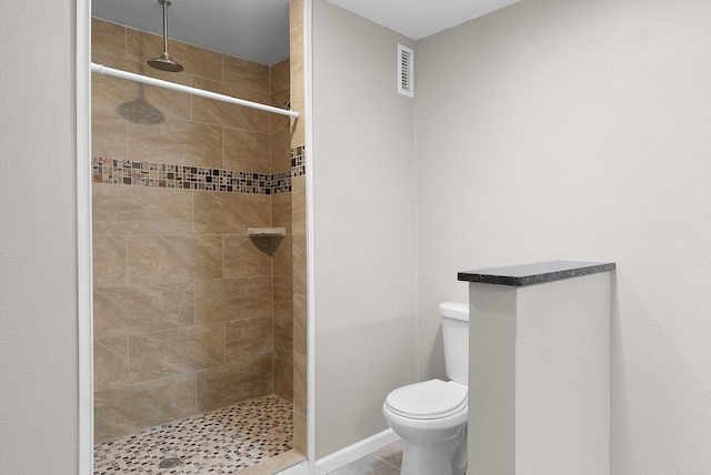 bathroom featuring tiled shower, tile patterned floors, and toilet