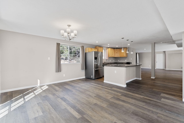 kitchen featuring dark hardwood / wood-style flooring, stainless steel refrigerator with ice dispenser, a notable chandelier, pendant lighting, and a kitchen island