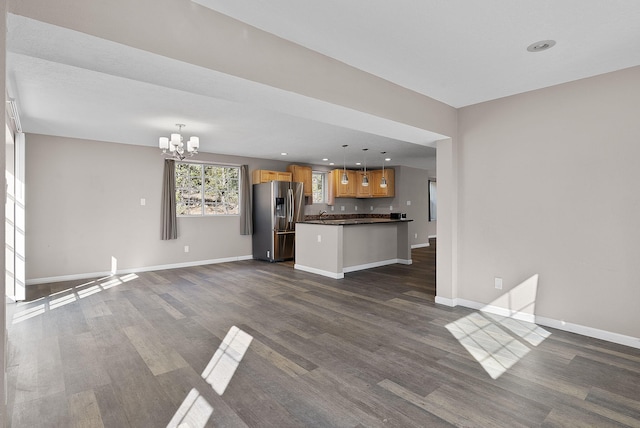 unfurnished living room featuring dark wood-type flooring and an inviting chandelier