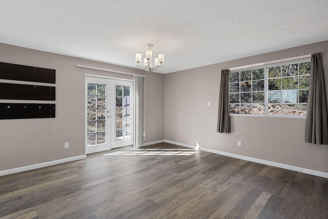 spare room with dark hardwood / wood-style floors, french doors, a textured ceiling, and a chandelier