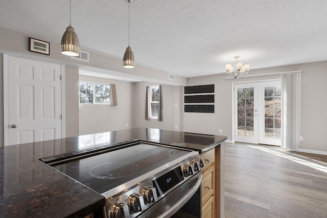 kitchen featuring a textured ceiling, hanging light fixtures, and electric stove