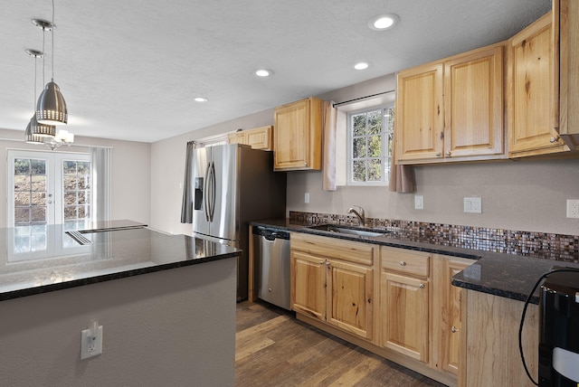 kitchen with appliances with stainless steel finishes, dark hardwood / wood-style flooring, french doors, sink, and pendant lighting