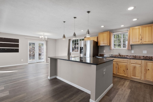 kitchen featuring plenty of natural light, sink, decorative light fixtures, a kitchen island, and stainless steel fridge with ice dispenser