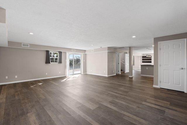 unfurnished living room featuring a textured ceiling and dark hardwood / wood-style flooring