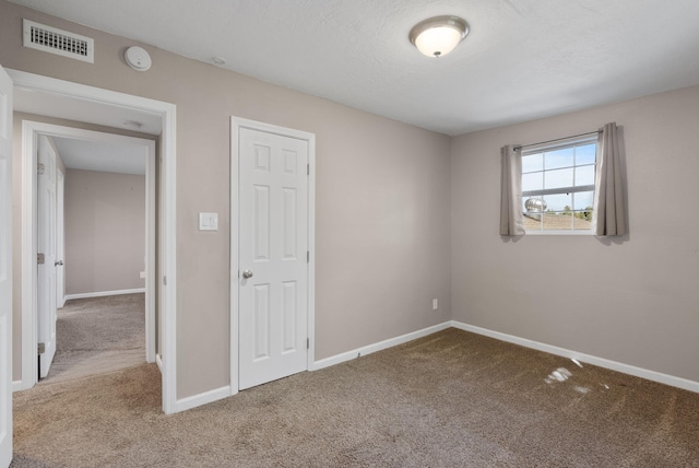 empty room with a textured ceiling and carpet floors