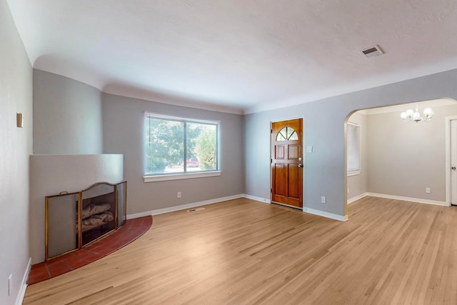 unfurnished living room with an inviting chandelier and light wood-type flooring