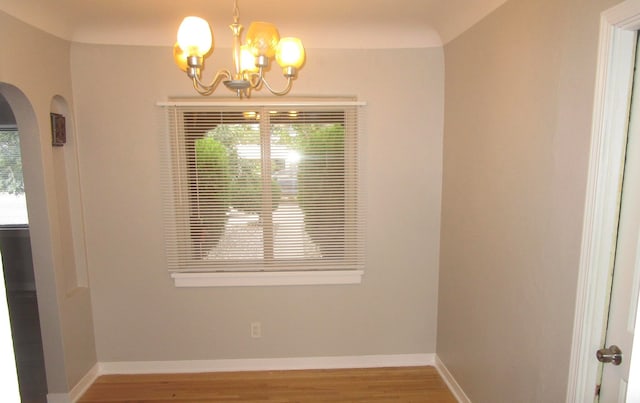 empty room with hardwood / wood-style flooring and a notable chandelier