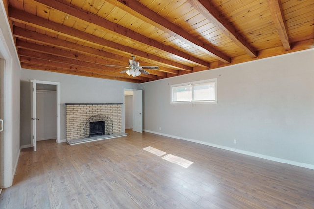 unfurnished living room featuring wood ceiling, beam ceiling, light hardwood / wood-style flooring, and a brick fireplace