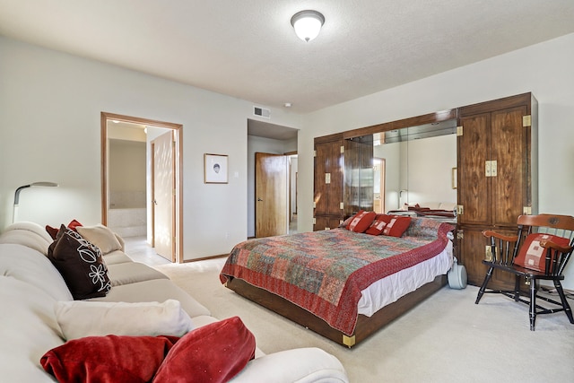 carpeted bedroom with connected bathroom and a textured ceiling