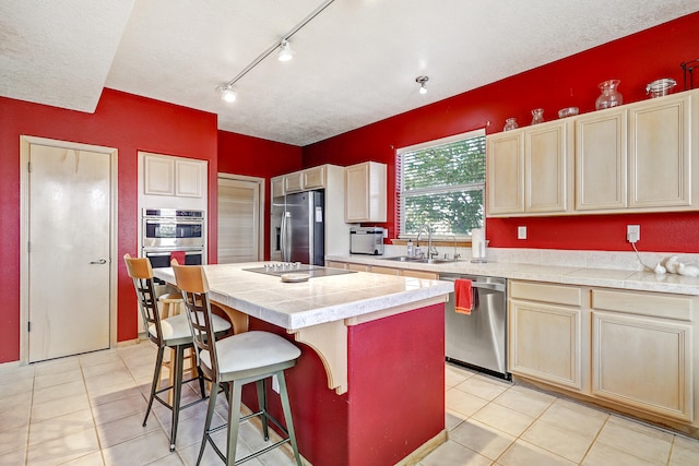 kitchen with sink, light tile patterned floors, stainless steel appliances, and a center island