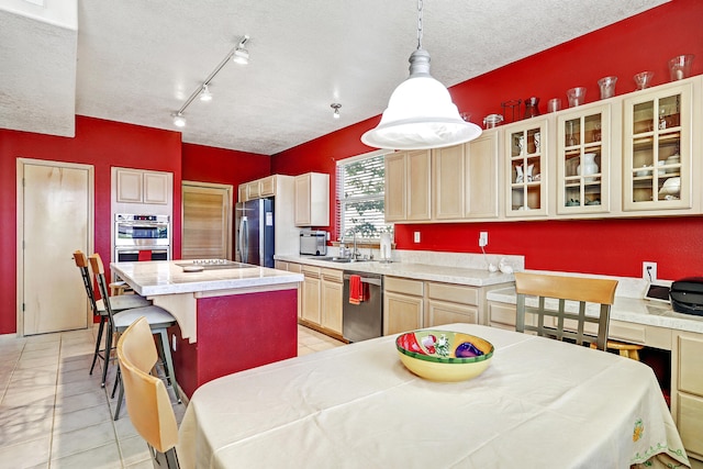 kitchen featuring a kitchen island, hanging light fixtures, stainless steel appliances, and a textured ceiling