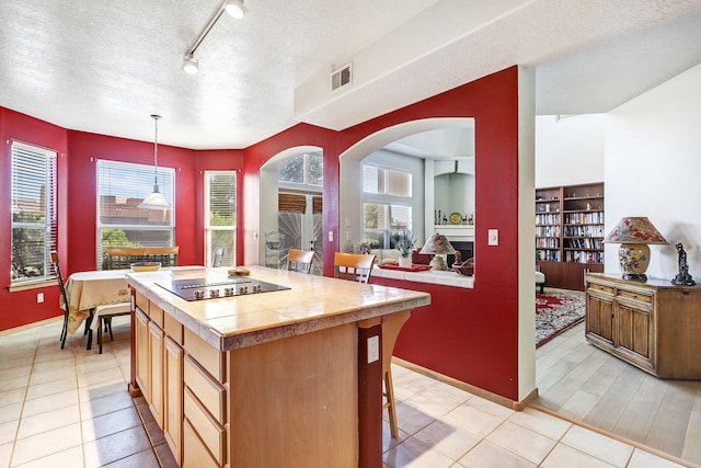 kitchen with light tile patterned flooring, a textured ceiling, decorative light fixtures, and a kitchen island