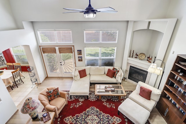 living room with ceiling fan, a high ceiling, and light wood-type flooring