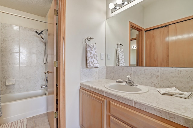 bathroom with backsplash, a textured ceiling, vanity, tiled shower / bath combo, and tile patterned flooring