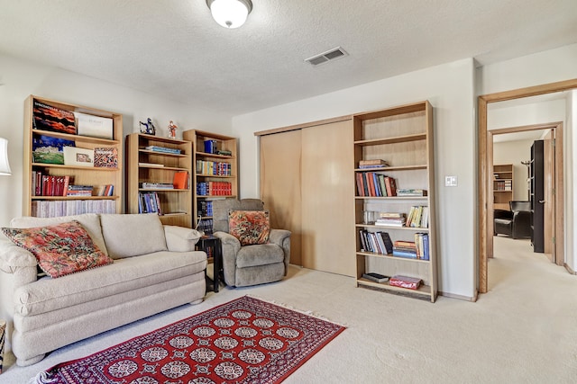 sitting room featuring a textured ceiling and light colored carpet