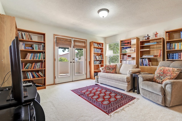 living area featuring french doors, a textured ceiling, and light colored carpet