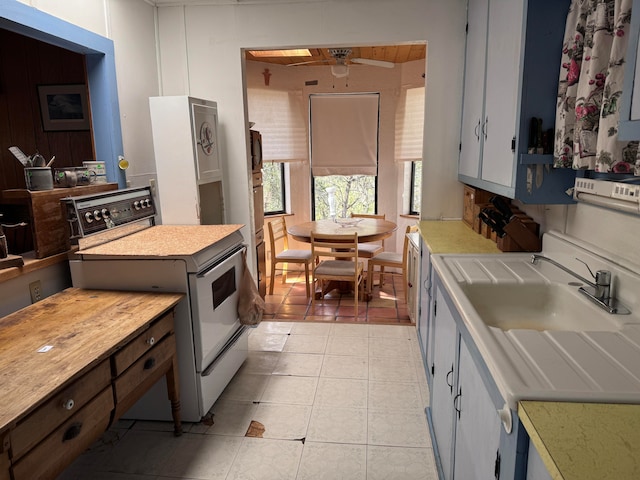 kitchen featuring sink, ceiling fan, light tile patterned floors, and white range oven