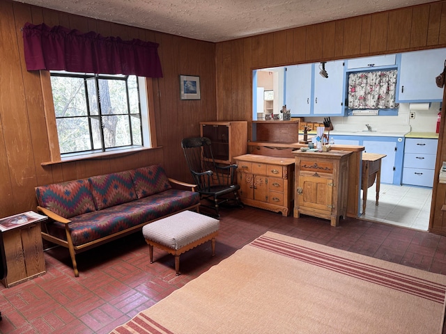 living room featuring wood walls, a textured ceiling, and sink