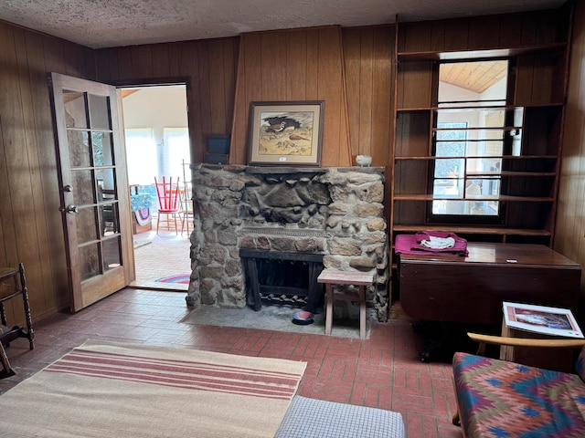 living room with wood walls, a textured ceiling, and a fireplace