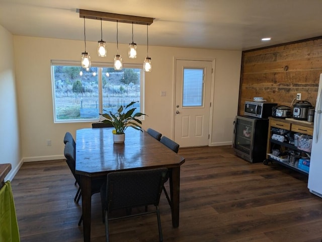 dining room featuring dark wood-type flooring, wine cooler, and wooden walls