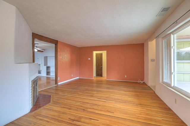 unfurnished living room featuring light hardwood / wood-style floors, a textured ceiling, and ceiling fan