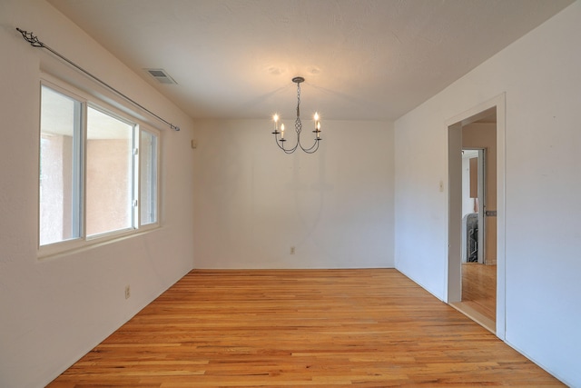 empty room with light hardwood / wood-style flooring and a notable chandelier