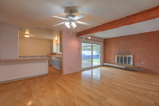 unfurnished living room featuring a brick fireplace, light hardwood / wood-style floors, ceiling fan, beam ceiling, and brick wall