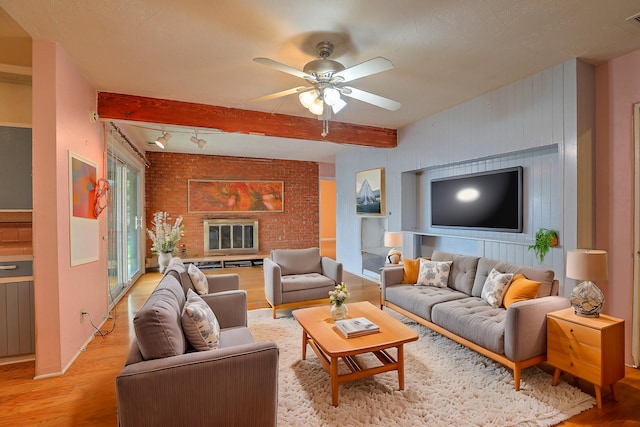 living room with a fireplace, beam ceiling, light wood-type flooring, and ceiling fan