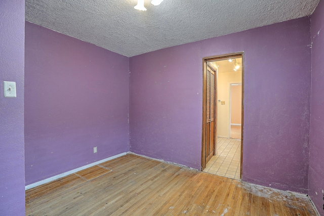 unfurnished room with a textured ceiling and light hardwood / wood-style flooring